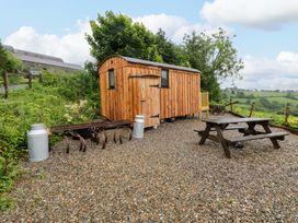 A wooden hut and picnic table in an outdoor area at The Hut in Llandysul