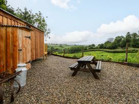 An outdoor area with a wooden cabin and picnic table at The Hut in Llandysul