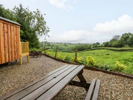 An outdoor scene with a wooden cabin and bench overlooking a landscape at The Hut in Llandysul
