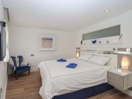 A bedroom with a bed, bedside tables, and a chair at 5 Sails in Dartmouth