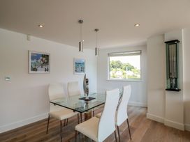 A dining room with a glass table and white chairs at 5 Sails in Dartmouth