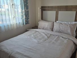 A bedroom with a bed and curtains at Unity Beach - Abi Ryedale in Burnham-on-Sea