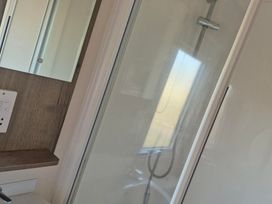 A shower and mirror in a bathroom at Unity Beach - Abi Ryedale Burnham-on-Sea