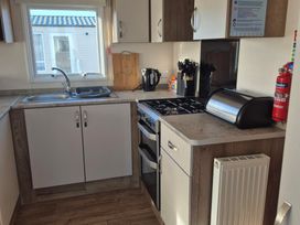 A kitchen with a sink, stove, and utensils at Unity Beach - Abi Ryedale in Burnham-on-Sea