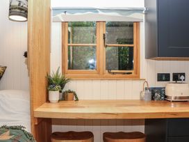 A kitchen with a wooden table and stools at Ridden Brake shepherds hut in Yelverton