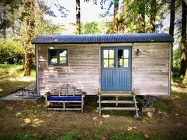 A wooden cabin with a door and window at Goldcrest in Postbridge