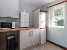 A kitchen with a microwave, fridge, and cupboard at Robin Hood Farmhouse in Keswick