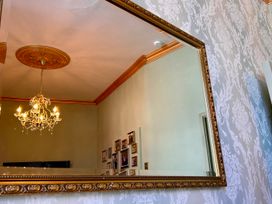 A mirror reflecting a chandelier and wall photos at Downton I in Alnwick