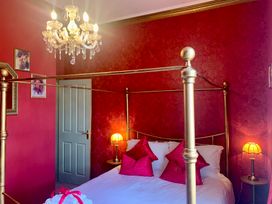 A bedroom with a four-poster bed and chandelier at Downton I in Alnwick