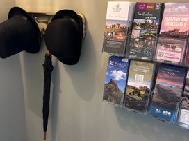 A wall display with hats, an umbrella, and tourist brochures at Downton I in Alnwick