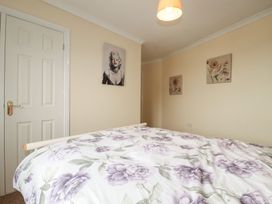 A bedroom with a bed and wall art at Treetops St Blazey