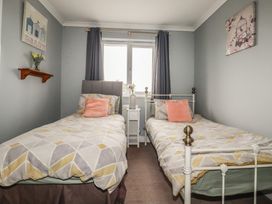A bedroom with two single beds and a bedside table at Treetops in St Blazey
