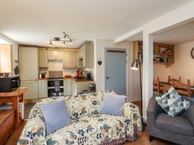 A living room with a sofa and kitchen area at Scoops’ Nook in Caernarfon