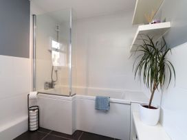 A bathroom with a bathtub, shower screen and plant at Scoops’ Nook Caernarfon