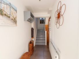 A hallway with a staircase and wall hooks at Scoops’ Nook in Caernarfon
