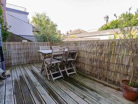A balcony with a wooden table and chairs at Scoops’ Nook in Caernarfon