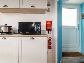 A kitchen with a microwave, slow cooker, fire blanket, and fire extinguisher at 31 Tregoney Hill Mevagissey