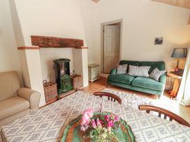 A living room with a fireplace wood stove and seating at The Coach House Cottage BALLYCOMMON