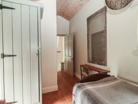 A bedroom with a bed and mirror at The Coach House Cottage BALLYCOMMON