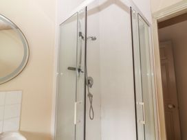 A shower enclosure with a mirror and tiles at The Coach House Cottage BALLYCOMMON