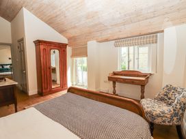 A bedroom with a bed a wardrobe and a chair at The Coach House Cottage BALLYCOMMON