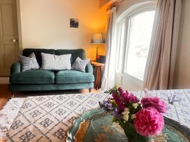 A living room with a green sofa and flowers on a table at The Coach House Cottage Ballycommon