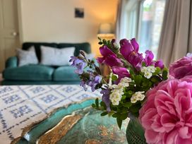 A living room with a vase of flowers and a green sofa at The Coach House Cottage Ballycommon