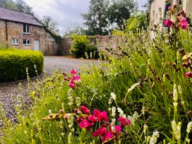 An outdoor space with flowers and a stone building at The Coach House Cottage in Ballycommon