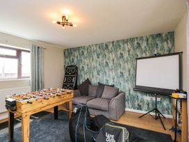 A snug room with a foosball table, sofa, and projector screen at 1 Stanway Road