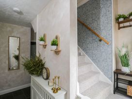 A hallway with a mirror, plants, and a staircase at 1 Stanway Road
