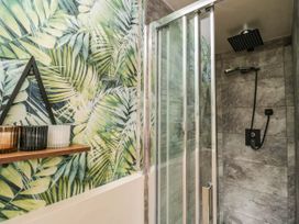 A bathroom featuring a shower with glass door and tropical wall decor at 1 Stanway Road