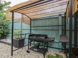 A barbecue setup with a metal grill and plant pots in the garden at 1 Stanway Road