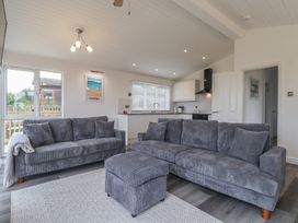 A living room with sofas and a kitchen area at Lodge 19 in Torpoint