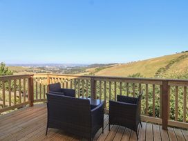 A deck with chairs and a table overlooking hills at Lodge 19 in Millbrook