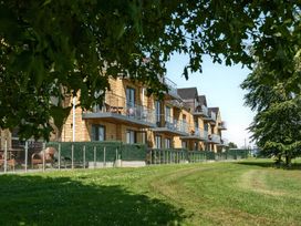 Multiple wooden buildings with balconies and grass area at Cotswolds Apartment, sleeps 4 in Chipping Norton