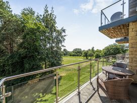 A balcony with a table and chairs overlooking grass and trees at Cotswolds Apartments 2B/S4 in Chipping Norton