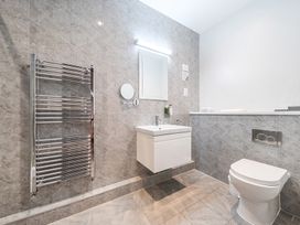 A bathroom with a sink, toilet, and mirror at Cotswolds Apartments 4B/S8 in Chipping Norton