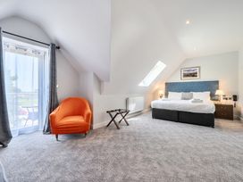 A bedroom with a bed and an orange chair at Cotswolds Apartments 4B/S8 in Chipping Norton