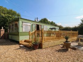 A caravan with a wooden deck at Buzzards Retreat in Wrexham