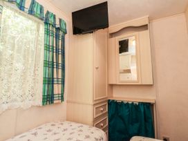 A bedroom with a bed, wardrobe and television at Buzzards Retreat in Wrexham