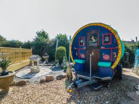 A garden with a caravan, stone path, and decorative objects at Buzzards Retreat in Wrexham