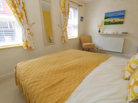 A bedroom with a bed, chair and mirror at Driftmark in Weymouth