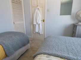 A bedroom with two beds and a robe hanging on the door at Driftmark in Weymouth