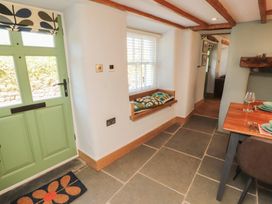 A hallway with a green front door and a dining table at Haws Bank Cottage in Coniston