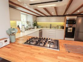 A kitchen with a gas stove, sink, and kitchen cabinets at Haws Bank Cottage in Coniston