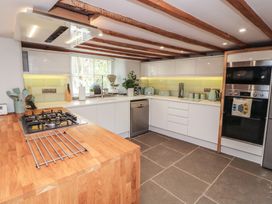 A kitchen with a gas stove and white cabinetry at Haws Bank Cottage in Coniston