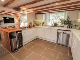 A kitchen with a gas stove and a wooden island at Haws Bank Cottage Coniston