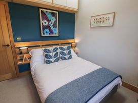 A bedroom with a bed and wall art at Haws Bank Cottage in Coniston