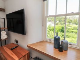 A living room with a television and view of the outdoors at Haws Bank Cottage in Coniston