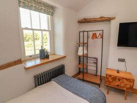 A bedroom with a window, clothes rack, and television at Haws Bank Cottage in Coniston
